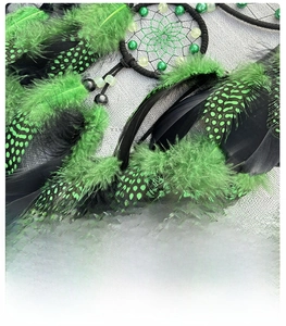 Detailed view of handmade dreamcatcher with green feathers and black spotted texture