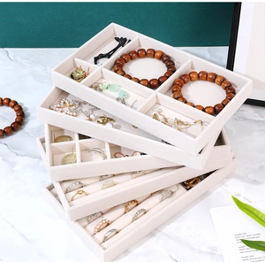 Detail view of stackable beige velvet jewelry trays showing functional ring and earring slots