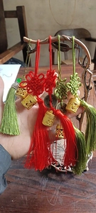 Detail van rode en groene Chinese knopen met holle metalen bedels en zijdeachtige kwastjes
