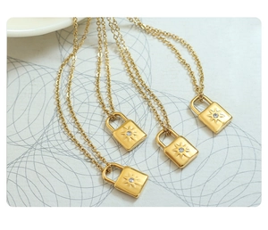 Close-up of golden lock pendants with sunburst texture and sparkling zircon inlay