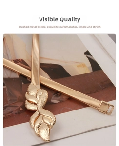 Macro detail of gold elastic metal waist chain featuring leaf-shaped buckle on magazine