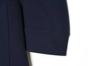 Detailed close-up of navy blue twill fabric texture and stitched cuff on a dress