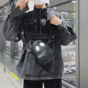 Detail of a black ghostly PU leather crossbody bag paired with a washed denim jacket