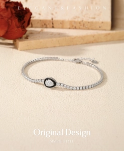 Macro detail of S925 sterling silver tennis bracelet with black enamel teardrop charm
