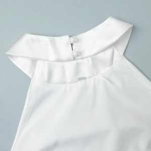 Détail d'un haut dos nu blanc en soie avec fermeture élégante par bouton perle
