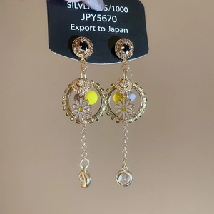 Detailed close-up of ethnic fan tassel earrings with daisy charm and blue beads