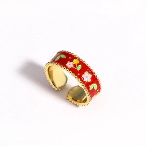 Detailed top view of red enamel flower ring with gold finish and adjustable open band