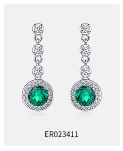 Macro detail of S925 silver emerald earrings with teardrop green gems and diamonds