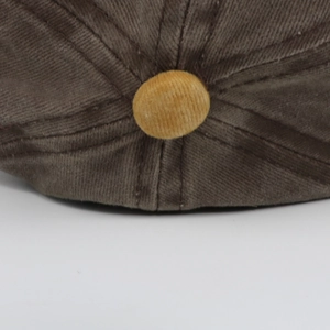 Detail of corduroy baseball cap top featuring a contrast yellow button and textured fabric
