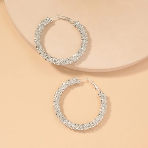 Detailed view of silver hoop earrings fully paved with sparkling crystals and rhinestones