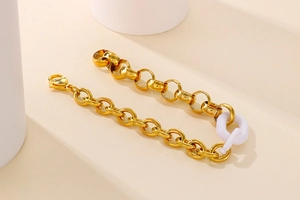 Vue détaillée du bracelet à maillons dorés avec anneau en résine sur support beige