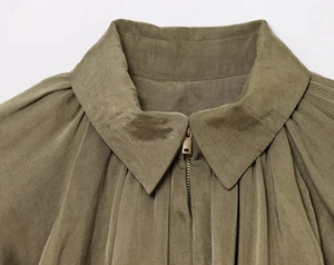 Détail d'une chemise en popeline vert olive avec col pointu et fermeture éclair en métal