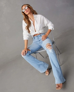 Détail du jean bleu clair à taille haute et jambes larges avec finitions déchirées