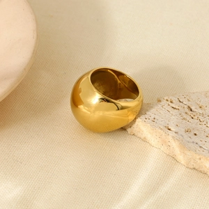 Detail of 18K gold plated sphere ring on natural stone and beige fabric texture