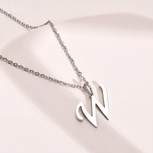 Detailed close-up of a silver titanium steel necklace featuring a letter W initial pendant