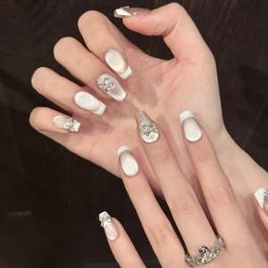 Macro view of champagne cat-eye press-on nails with white French tips and 3D bows