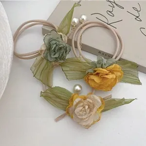 Detail view of handmade fabric flower hair clips with pearls and gold chains in three colors
