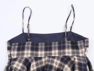 Detail of adjustable spaghetti straps and navy plaid pattern on a casual summer top