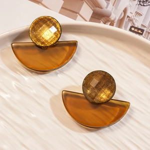 Detail of fan-shaped resin earrings with golden brown checkered stud on beige plate