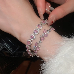 Detail of pink heart-shaped and oval zircon bracelets worn on a model's wrist