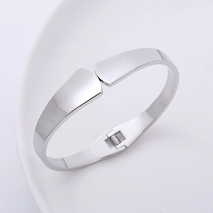 Close-up of polished silver minimalist hinged bangle on a white decorative plate