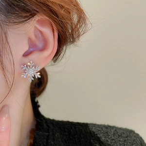 Macro view of snowflake pearl earrings with cubic zirconia on a model ear