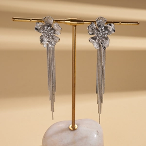 Detail of silver flower tassel earrings with zircons and pearls on a gold display stand