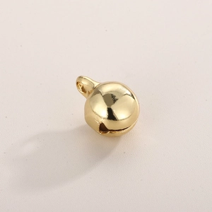 Detailed close-up of a single golden round metal bell charm with smooth polished finish