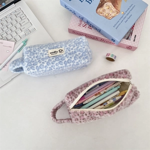 Close-up of leopard print plush cosmetic pouches in light blue and purple with zipper detail
