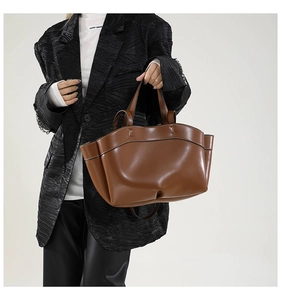 Vista dettagliata della borsa tote in pelle marrone con cuciture e dettagli del manico