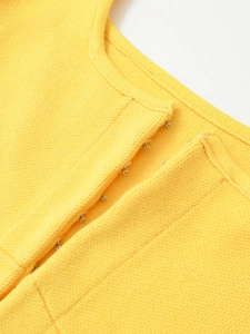 Macro shot of metal hook-and-eye closure on a yellow knit top with detailed texture