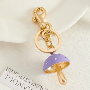 Detail van een paarse paddenstoel hanger met goudkleurige afwerking en paarse strass