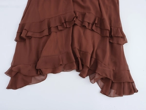 Dettaglio macro delle balze a strati in chiffon marrone scuro sull'orlo di un maxi abito