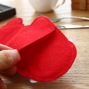 Christmas silverware holder made of red felt showing edge stitching and texture on wood table