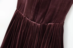 Detailed close-up of dark purple velvet dress showing waist seams and draped pleats