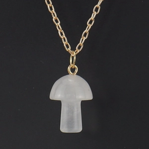 Detailed macro view of white crystal mushroom pendant on a delicate gold metal chain link