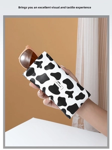 Close-up of cow print leather glasses case with milky label and snap closure