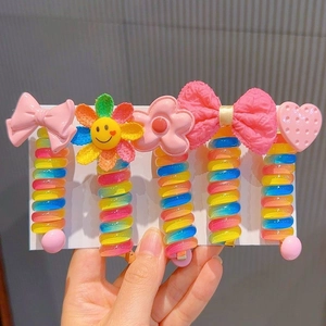 Detailed view of five colorful rainbow spiral hair ties with cute cartoon ornaments