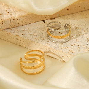 Detail of 18K gold triple-layered open rings with hammered texture on travertine stone