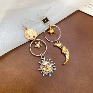 Dettaglio di orecchini nappe con sole e luna su elegante tessuto di seta