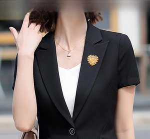 Baroque gold heart brooch with intricate carving pinned on a black business suit blazer