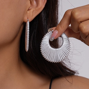 Close-up of bohemian silver textured hollow round hoop earrings worn by a model