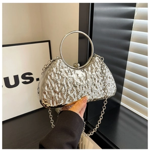 Close-up of silver evening clutch with wave-texture metal surface and round handle