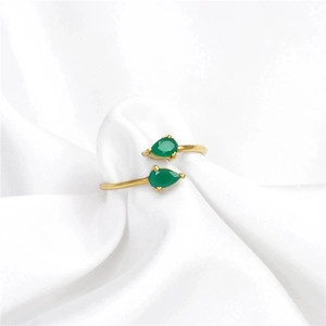 Macro shot of gold S925 silver ring with drop-shaped green zircon on white fabric