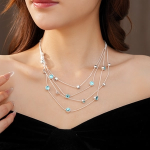 Detail of a silver layered necklace featuring elegant blue circular gemstones on the neck