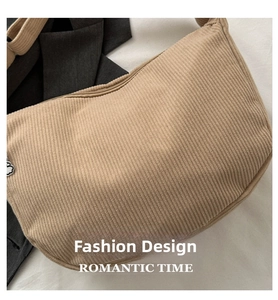 Detail of beige corduroy hobo bag with zip closure and white cloud charm pendant