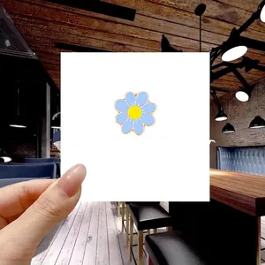 Detailed view of a blue daisy enamel brooch with yellow center and gold plating