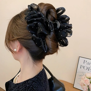Detail view of a large black mesh bow hair claw clip styled on a model's low bun hairstyle