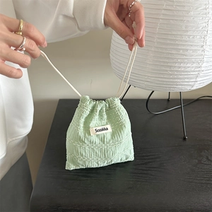 Detail of mint green drawstring pouch in textured seersucker with woven logo label