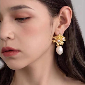 Gros plan d'une femme portant des boucles d'oreilles fleur dorées et perles